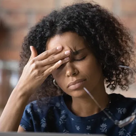 A woman with a headache pinching her nose bridge to alleviate pain